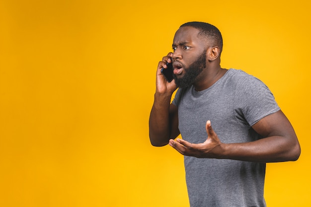 Junger Afroamerikanermann, der Smartphone verwendet, gestresst, schockiert mit Scham und Überraschungsgesicht, wütend und frustriert. Angst und Aufregung wegen Irrtums.