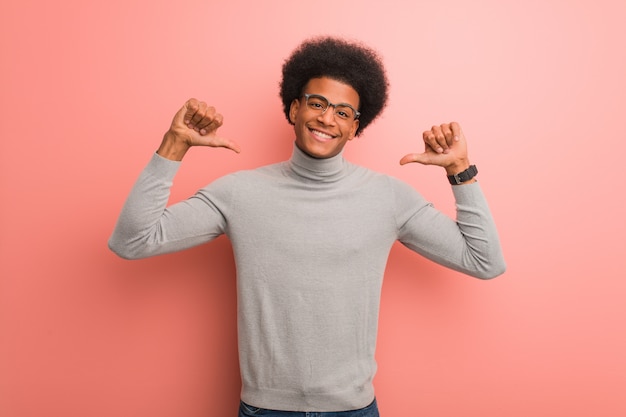 Junger Afroamerikanermann über einer rosa Wand Finger zeigend, Beispiel zu folgen