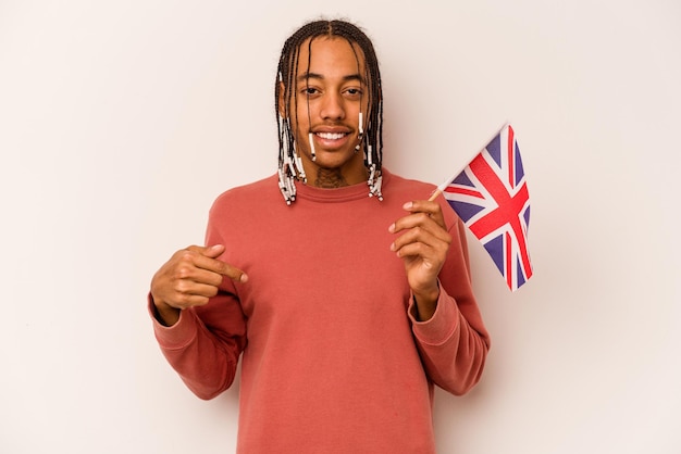 Junger afroamerikanischer Mann, der eine englische Flagge isoliert auf weißem Hintergrund hält und mit der Hand auf einen Hemdkopienraum zeigt, stolz und selbstbewusst
