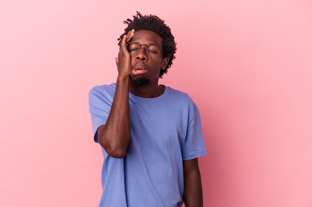 Junger afroamerikanischer Mann einzeln auf rosafarbenem Hintergrund müde und sehr schläfrig, die Hand auf dem Kopf halten.