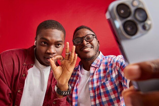 Junger afroamerikanischer Mann freut sich mit den Händen vor der Kamera, isoliert auf rotem Hintergrund, Studioporträt