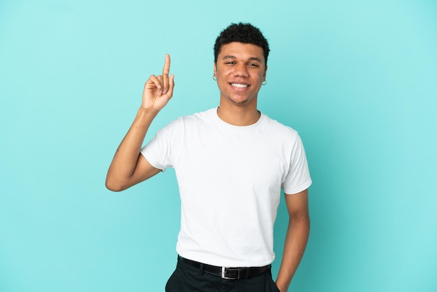 Junger afroamerikanischer Mann isoliert auf blauem Hintergrund, der auf eine großartige Idee zeigt
