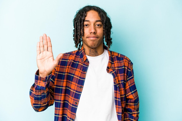 Junger afroamerikanischer Mann isoliert auf blauem Hintergrund lächelnd fröhlich und zeigt Nummer fünf mit den Fingern