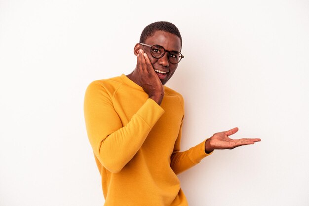 Junger afroamerikanischer Mann isoliert auf weißem Hintergrund beeindruckt mit Kopienraum auf der Handfläche