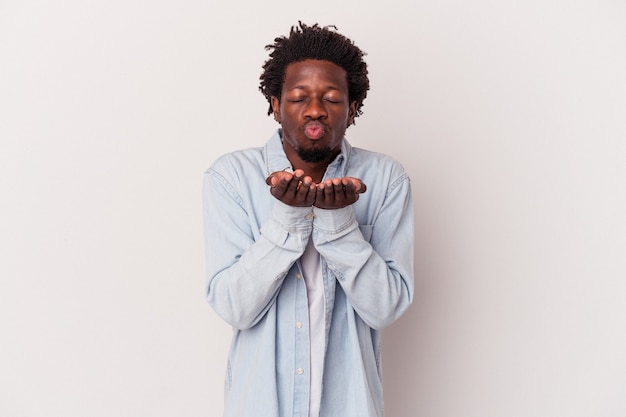 Junger afroamerikanischer Mann isoliert auf weißem Hintergrund, der Lippen faltet und Handflächen hält, um Luftkuss zu senden.
