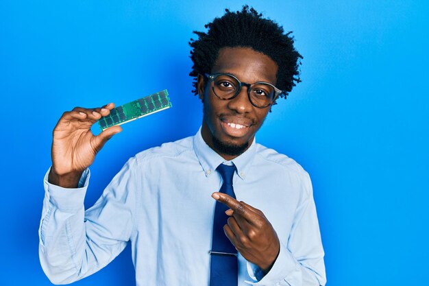 Junger afroamerikanischer Mann mit Computer-RAM, lächelnd und glücklich zeigend mit Hand und Finger