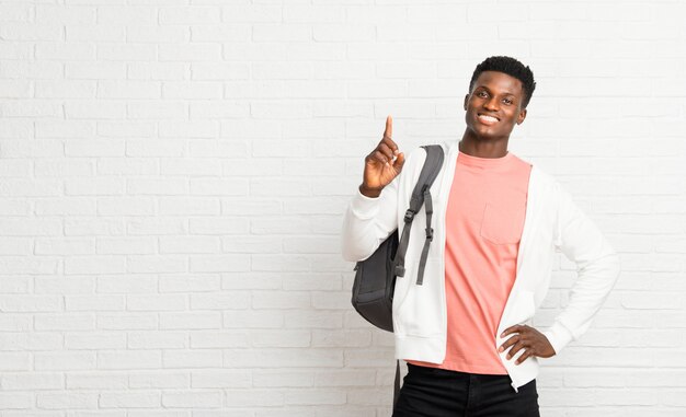 Junger afroer-amerikanisch mannstudent, der einen finger im zeichen des besten zeigt und anhebt