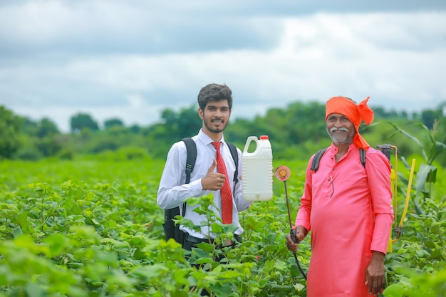Junger Agronom mit Landwirt, der Düngerflasche im Feld zeigt