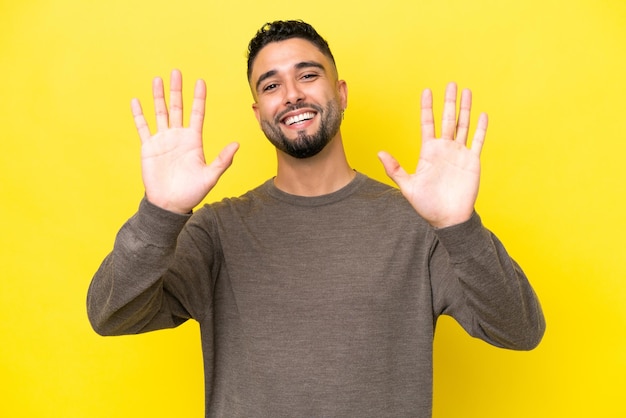 Junger arabischer gutaussehender Mann isoliert auf gelbem Hintergrund, der zehn mit den Fingern zählt