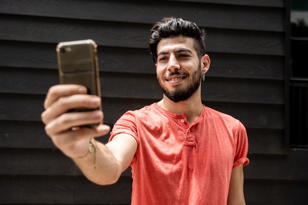 Junger arabischer Mann, der ein Selfie mit einem Handy in der Straße macht