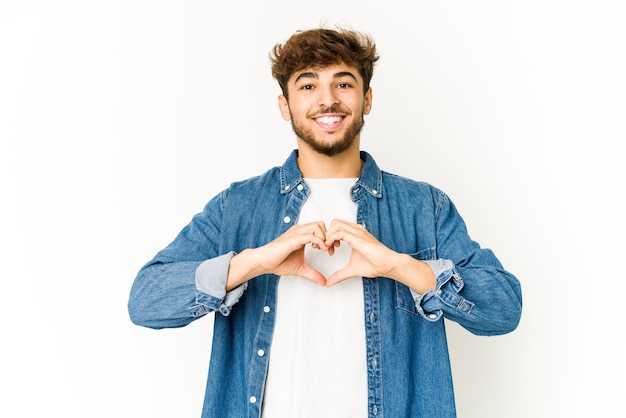 Junger arabischer Mann, der lächelt und eine Herzform mit Händen zeigt.