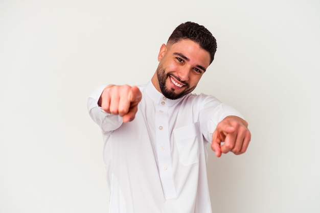 Junger arabischer Mann, der typische arabische Kleidung lokalisiert auf weißem Hintergrund freudiges Lächeln trägt, zeigt nach vorne.