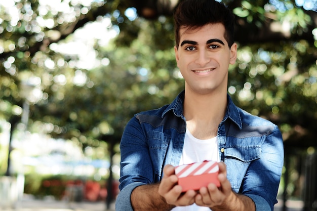 Junger arabischer Mann mit einer roten Geschenkbox