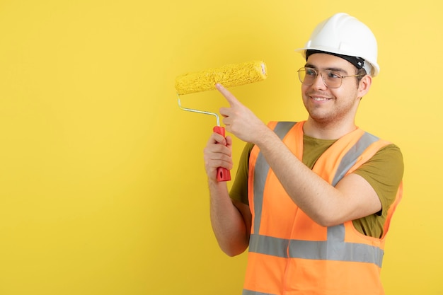 junger Arbeiter im Helm, der Malrolle berührt.