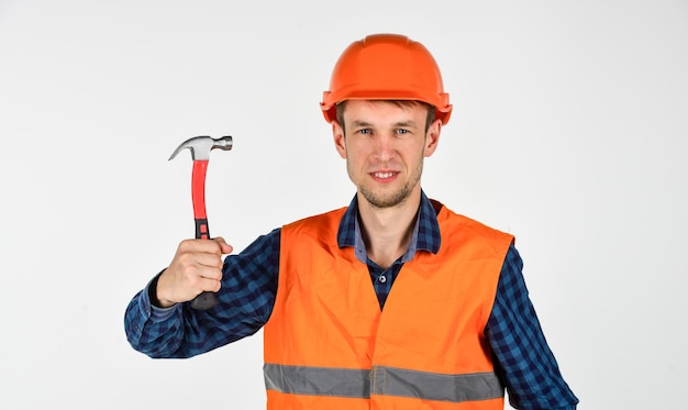 Junger Arbeiter ist Ingenieur-Hilfsmechaniker in Uniform Mann arbeitet mit Hammer echter Bauarbeiter in Helm Tischler bereit zu arbeiten Reparaturgeräte für Bauwerkzeuge Er liebt seinen Job