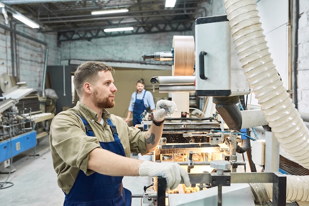 Junger Arbeiter mit Maschine in der Fabrik