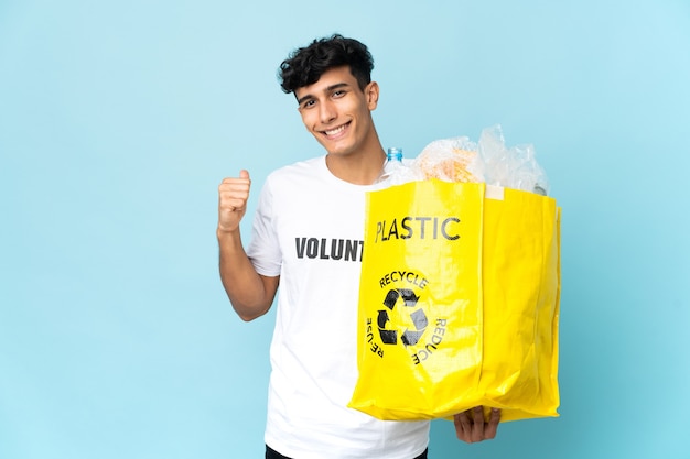 Junger argentinischer Mann, der eine Tasche voll Plastik hält, die zur Seite zeigt, um ein Produkt zu präsentieren