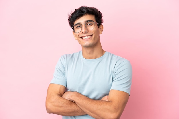 Junger argentinischer Mann isoliert auf rosa Hintergrund mit Brille mit fröhlichem Ausdruck