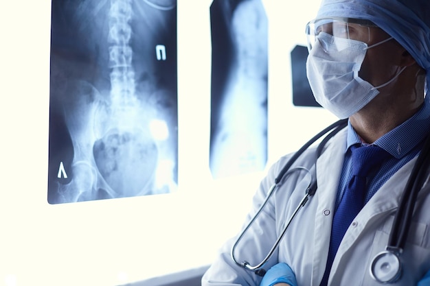 Junger Arzt, der ein Röntgenbild auf isoliertem weißem Hintergrund betrachtet