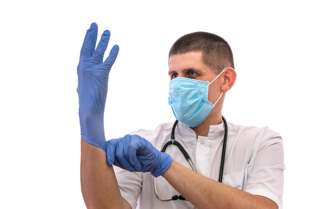 Junger Arzt in Uniform, der sich auf die Arbeit vorbereitet und Handschuhe auf weißem Hintergrund anzieht