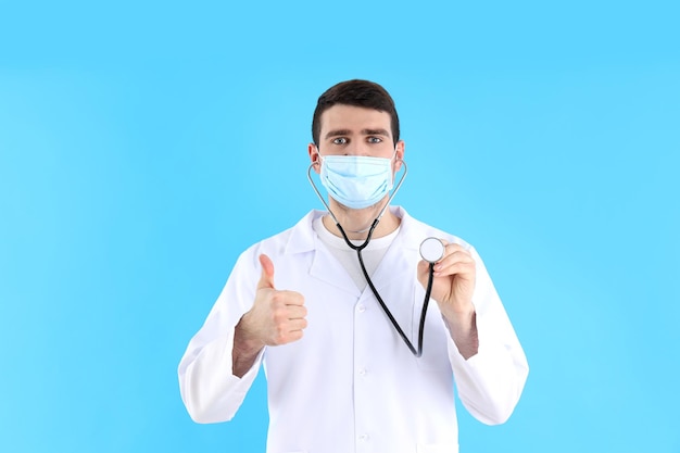 Junger Arzt mit Stethoskop auf blauem Hintergrund
