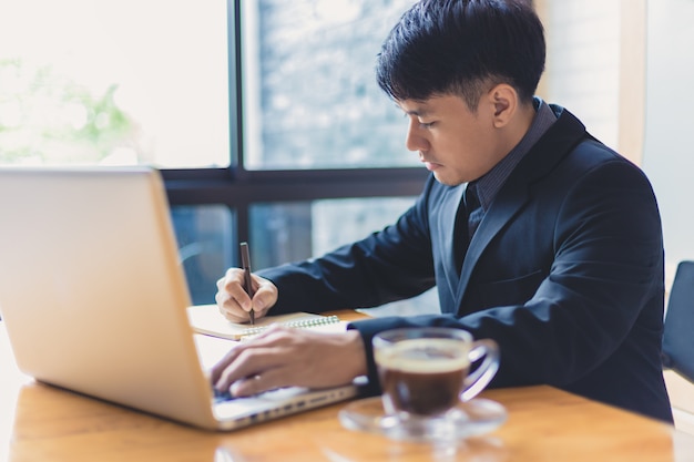 Junger asiatischer Exekutivgeschäftsmann, der an seinem Computer in seinem Büro arbeitet