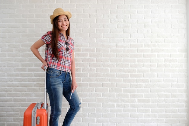 Junger asiatischer Frauenreisender, der intelligentes Telefon und Gepäck im Reinraum hält.