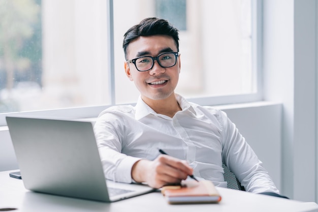 Junger asiatischer Geschäftsmann, der im Büro arbeitet