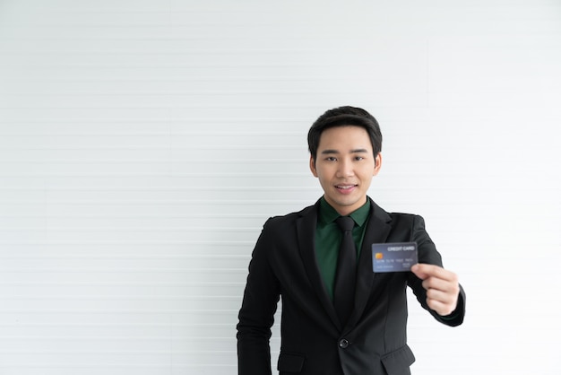 Junger asiatischer Geschäftsmann, der Kreditkarte auf Weiß hält