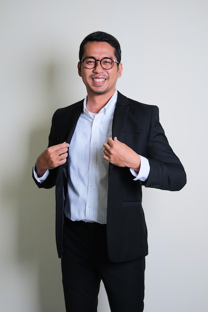 Junger asiatischer Geschäftsmann, der stolze Geste zeigt, indem er seinen Anzug berührt
