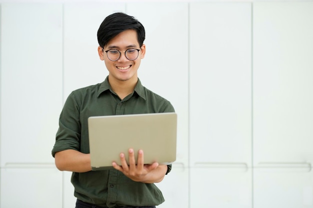 Junger asiatischer Geschäftsmann oder Student, der online am Computer-Laptop arbeitet