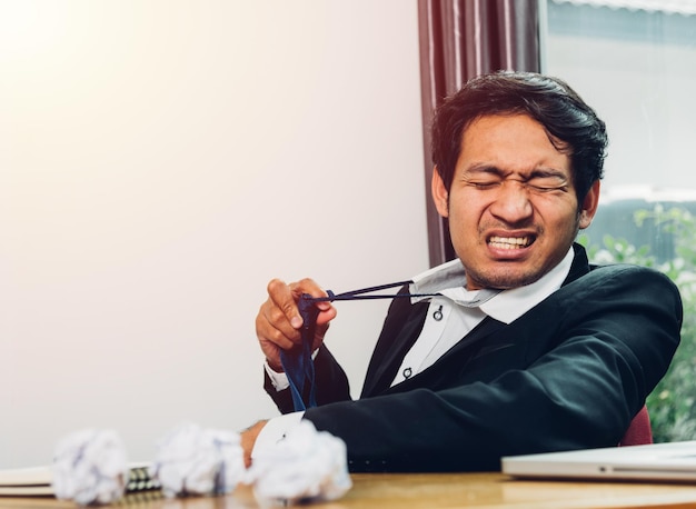 Junger asiatischer Geschäftsmannmanager ist frustriert, dass er nach der Arbeit lange Zeit müde ist