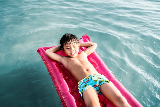 Junger asiatischer Junge in einem Swimmingpool