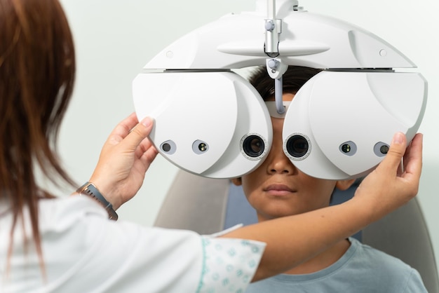 Junger asiatischer Junge mit einem modernen Phoropter bei einer Optometristen-Beratung