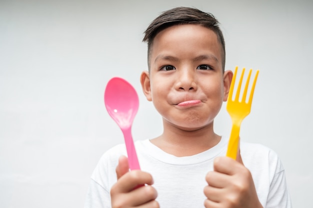 junger asiatischer Junge mit Foek und Löffel aufgeregt zu essen