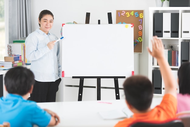 Junger asiatischer Lehrer fragen Fragenjunge Kinder im Klassenzimmer.