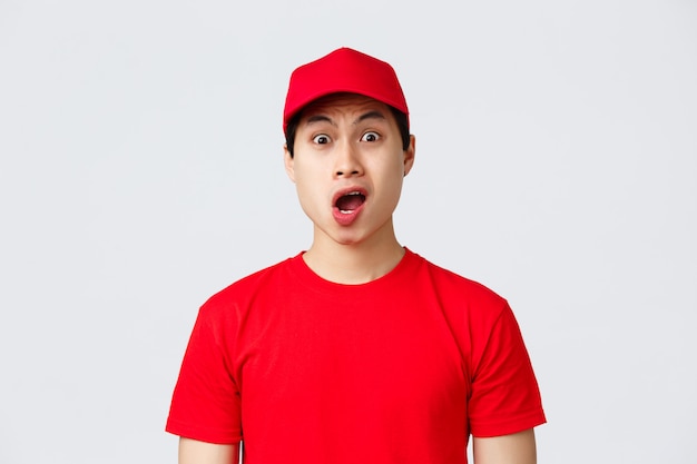 Junger asiatischer Lieferbote in einem roten T-Shirt