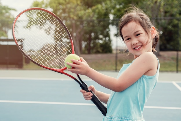 Junger asiatischer Mädchentennisspieler auf blauem Gericht im Freien