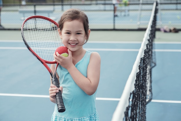 Junger asiatischer Mädchentennisspieler auf blauem Gericht im Freien