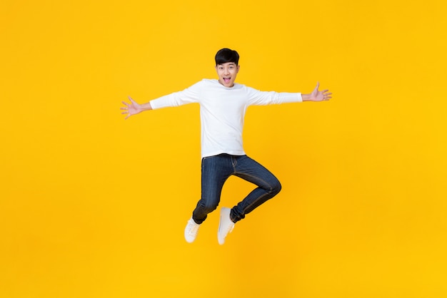 Junger asiatischer Mann beim Springen der zufälligen Kleidung