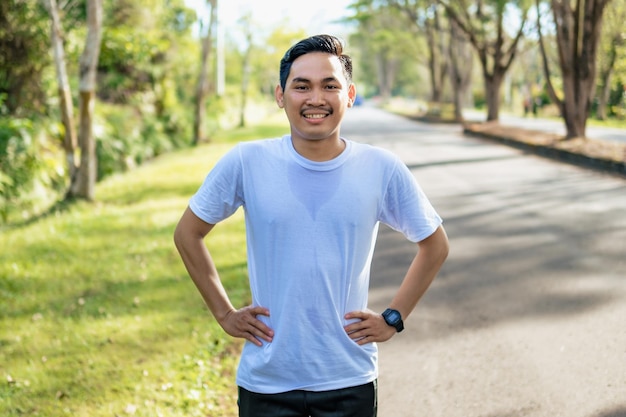 Junger asiatischer Mann, der Dehnübungen macht, um sich auf das Laufen in der Natur vorzubereiten Gesunder Lebensstil