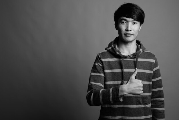 Junger asiatischer Mann, der gestreiften Kapuzenpulli trägt