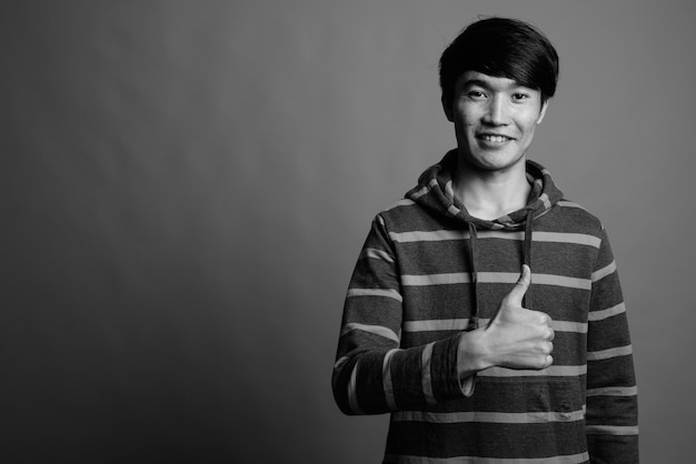 Junger asiatischer Mann, der gestreiften Kapuzenpulli trägt