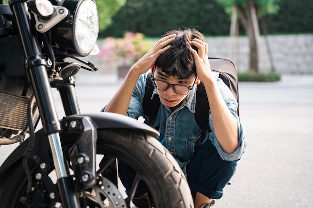 Junger asiatischer Mann, der Motorrad repariert