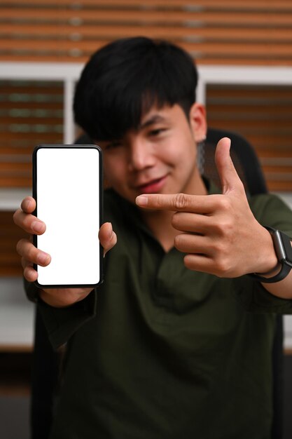 Junger asiatischer Mann, der Smartphone mit leerem Bildschirm für Werbung zeigt