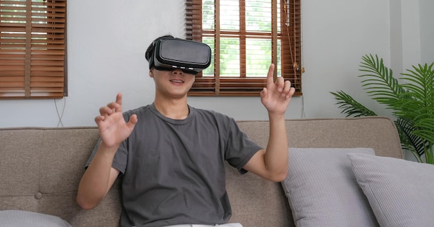 Junger asiatischer Mann, der während des VR-Erlebnisses die Luft berührt