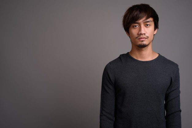 Junger asiatischer Mann gegen graue Wand