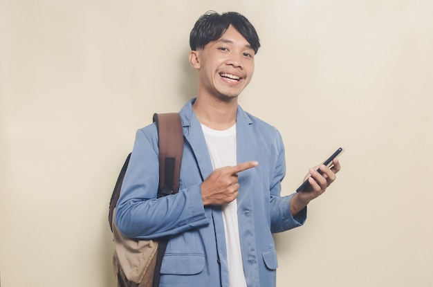 Junger asiatischer Mann mit College-Anzug, Tragetasche und Telefon auf isoliertem Hintergrund