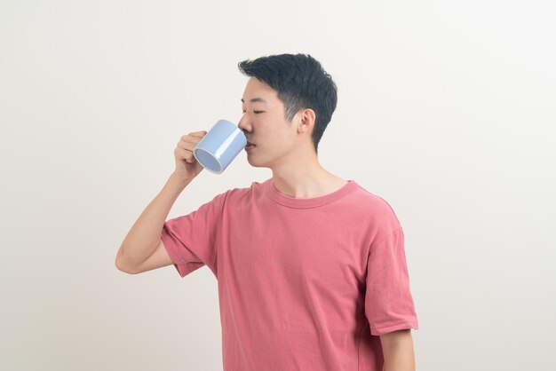 junger asiatischer Mann mit Kaffeetasse mit lächelndem Gesicht auf weißem Hintergrund
