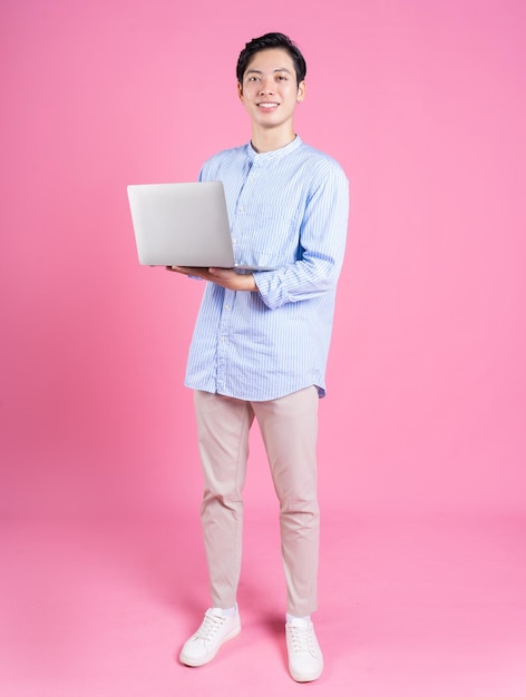 Junger asiatischer Mann mit Laptop im Hintergrund